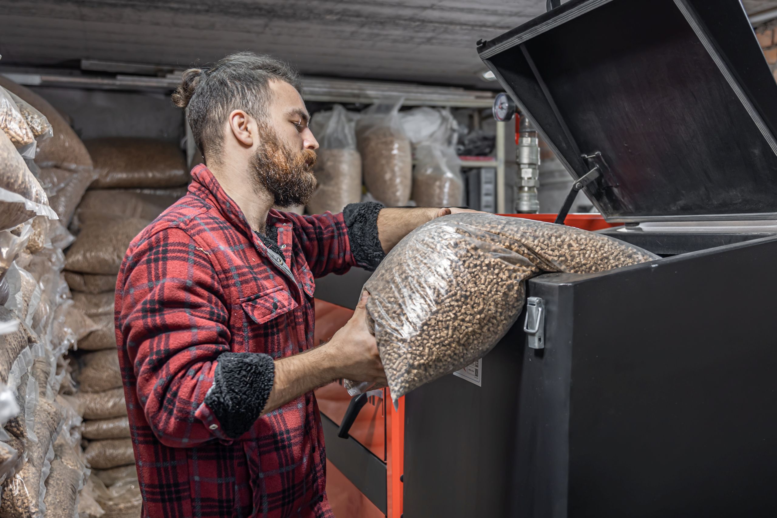 man-loads-pellets-solid-fuel-boiler-working-with-biofuels-economical-heating