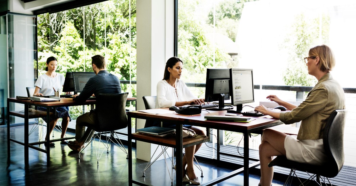 Business people working at desks by window in office